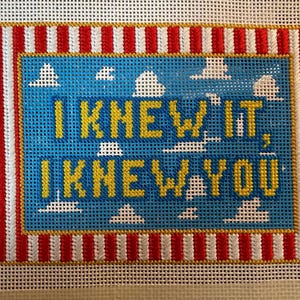 May include: A needlepoint canvas featuring a blue sky background with white clouds and the yellow text I KNEW IT, I KNEW YOU. The design is framed by a border of vertical red and white stripes, all set against a white grid mesh background.