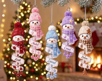 Puede incluir: Cinco adornos colgantes de muñecos de nieve con gorros y bufandas de punto, cada uno con una cinta en espiral con un nombre: Keith, Mabel, Lionel, Coral y Belen. Los muñecos de nieve tienen temas de colores únicos en rojo, rosa, azul, morado y beige.