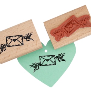 Busta e francobollo a forma di cuore, tenuti da simpatici uccellini per attraversare la posta e un regalo per lei