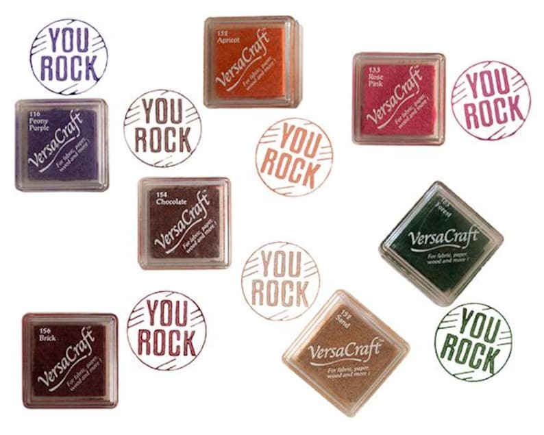K&ouml;nnte beinhalten: Sortiment von zehn Stempelkissen in verschiedenen Farben, jedes mit dem Text "VersaCraft" und "You Rock" auf dem Kissen. Die Stempelkissen sind quadratisch und rechteckig.