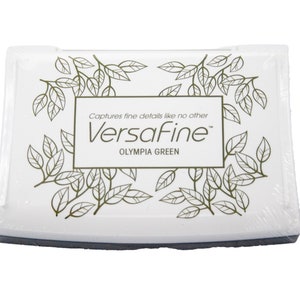 Puede incluir: Tinta blanca con un dise&ntilde;o de hoja de oro y el texto "Captures fine details like no other VersaFine Olympia Green".