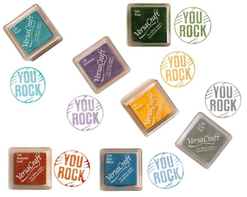 K&ouml;nnte beinhalten: Sortiment von zehn Stempelkissen in verschiedenen Farben, jedes mit dem Text "VersaCraft" und "You Rock" auf dem Kissen bedruckt. Die Stempelkissen sind in einem Kreis auf wei&szlig;em Hintergrund angeordnet.