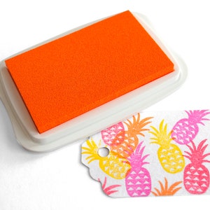 Pu&ograve; includere: Tavoletta d'inchiostro arancione con una custodia in plastica bianca e un'etichetta bianca con un motivo a ananas stampato in rosa, giallo e arancione.