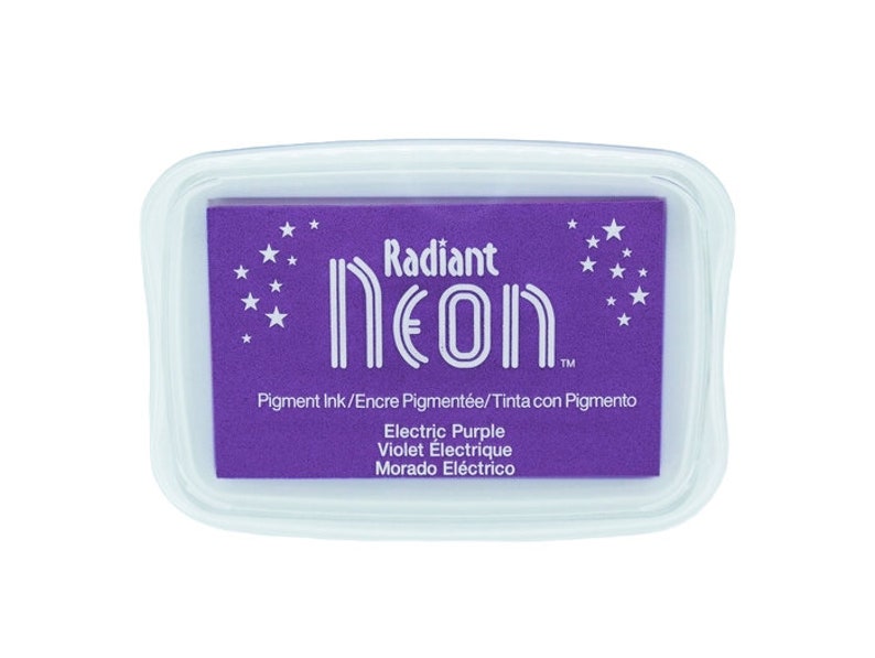 Pu&ograve; includere: Un tampone d'inchiostro viola con il testo "Radiant Neon" e le parole "Electric Purple, Violet &Eacute;lectrique, Morado El&eacute;ctrico" in bianco. Il tampone d'inchiostro &egrave; circondato da una custodia di plastica trasparente.