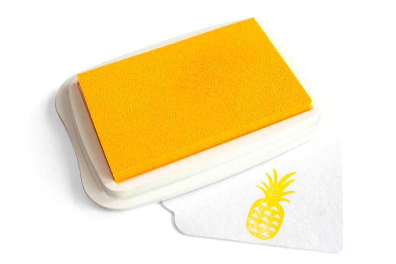 Pu&ograve; includere: Un tampone d'inchiostro giallo con una custodia in plastica bianca e un timbro di ananas giallo su una superficie bianca.