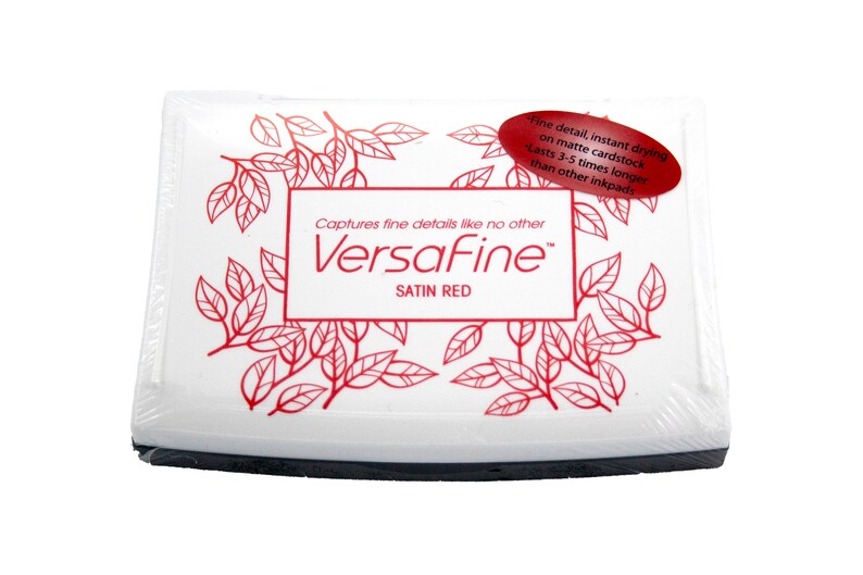 Puede incluir: Una almohadilla de tinta blanca con una etiqueta roja que dice "Captures fine details like no other VersaFine Satin Red". La etiqueta tiene un dise&ntilde;o floral rojo alrededor de los bordes.