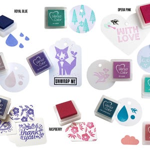 Pode incluir: Conjunto de almofadas de tinta VersaColor em v&aacute;rias cores, incluindo azul royal, rosa &oacute;pera, framboesa e lil&aacute;s. As almofadas de tinta est&atilde;o dispostas sobre um fundo branco com v&aacute;rios elementos de papel decorativos, incluindo etiquetas, cora&ccedil;&otilde;es e c&iacute;rculos. As almofadas de tinta s&atilde;o ideais para carimbar e artesanato.