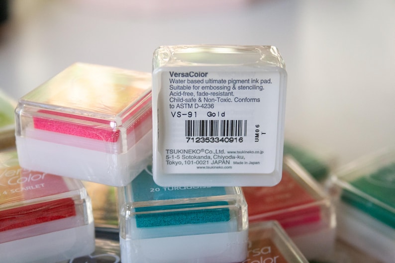 Pode incluir: Uma almofada de tinta VersaColor na cor dourada. A almofada de tinta est&aacute; em um recipiente de pl&aacute;stico transparente com um r&oacute;tulo branco. O r&oacute;tulo inclui o nome da marca, a cor e as informa&ccedil;&otilde;es do produto. A almofada de tinta &eacute; livre de &aacute;cidos, resistente ao desbotamento, segura para crian&ccedil;as e n&atilde;o t&oacute;xica.