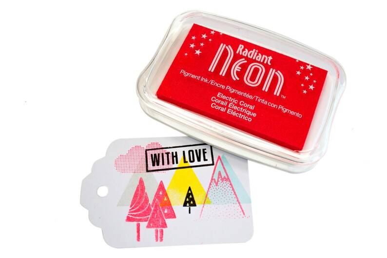 Pu&ograve; includere: Un tampone d'inchiostro rosso con il testo "Radiant Neon" e "Electric Coral" in bianco. Il tampone d'inchiostro &egrave; in una custodia di plastica trasparente. Uno sfondo bianco con il testo "WITH LOVE" e un design rosa e blu.