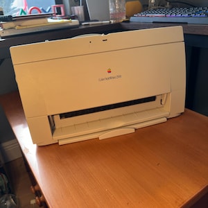 May include: A beige Apple Color StyleWriter 2500 inkjet printer with a rectangular body, a paper feed slot, and a front-loading output tray. The device features the classic multi-colored Apple logo and the model name printed on the front panel.