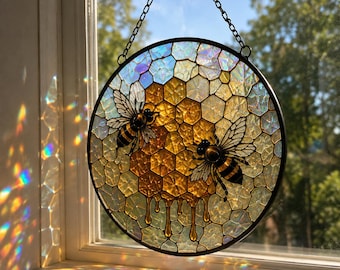 May include: A circular stained glass suncatcher featuring a honeycomb pattern with two bees. The center displays amber-colored honeycombs with dripping honey, surrounded by iridescent, textured glass pieces. It hangs from a black metal chain.