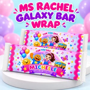 May include: Two rectangular candy bar wrappers featuring a colorful Ms. Rachel theme. The design includes cartoon characters, a yellow bus, balloons, and stars on a light blue background. The text reads CAN YOU SAY, MICHELLE, and HAPPY 1ST BIRTHDAY.
