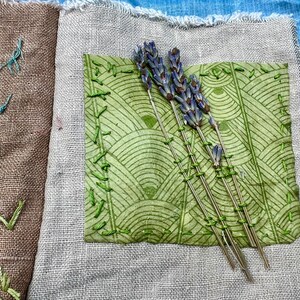 Puede incluir: Un diario de tela hecho a mano con una cubierta de patr&oacute;n verde y marr&oacute;n. El diario est&aacute; decorado con flores de lavanda secas y costuras verdes.