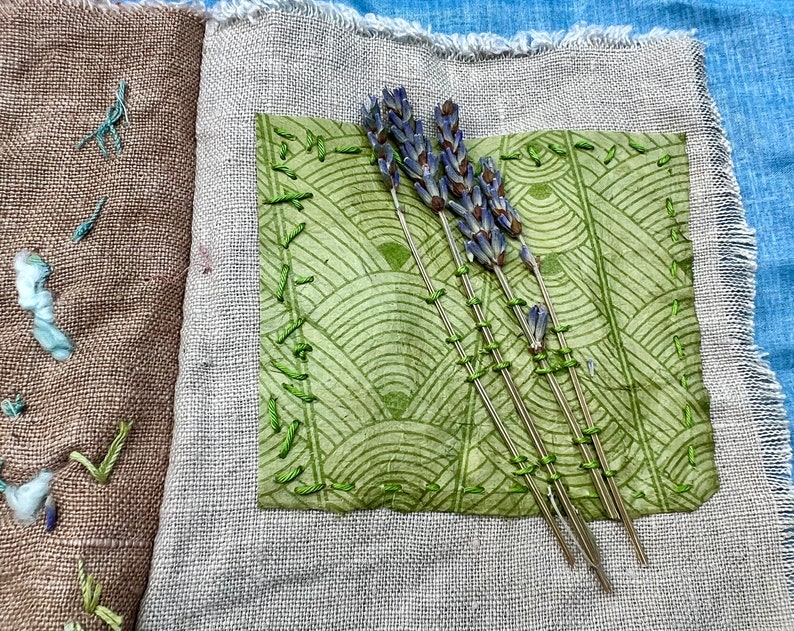 Puede incluir: Un diario de tela hecho a mano con una cubierta de patr&oacute;n verde y marr&oacute;n. El diario est&aacute; decorado con flores de lavanda secas y costuras verdes.