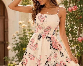 May include: A cream-colored mini dress featuring a smocked bodice and thin spaghetti straps. The fabric is decorated with a floral pattern in shades of pink, dark gray, and green. The skirt has a tiered design with a ruffled hemline at the bottom.