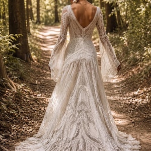 May include: A floor-length ivory lace gown featuring long bell sleeves, a deep V-shaped back, and a fitted bodice that transitions into a flowing skirt with a train. The intricate lace pattern covers the entire garment, highlighting the detailed floral and leaf motifs throughout the fabric design.