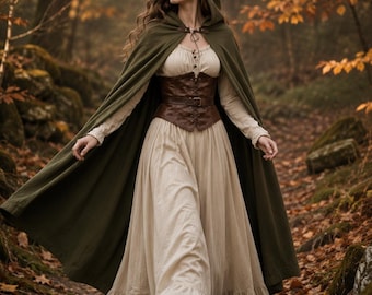 May include: A floor-length olive green hooded cloak worn over a cream-colored long-sleeved dress with a ruffled hem. A brown leather corset with front lacing and a buckle belt is worn over the dress. The cloak is fastened at the neck with a clasp.