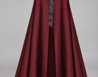 May include: A floor-length, deep burgundy hooded cloak featuring a smooth, solid-colored fabric. The garment is secured at the neck with a thin, black satin ribbon tied into a bow, allowing the front to remain open in a long, flowing silhouette.