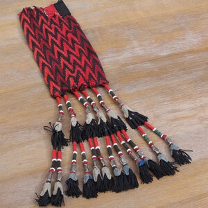 May include: A red and black woven fabric pouch with a fringe of black tassels and silver beads.