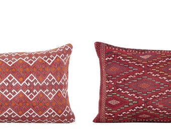 May include: Two rectangular throw pillows with geometric patterns. The pillow on the left is red with white geometric designs. The pillow on the right is red with a darker red and blue geometric design.