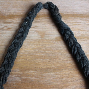 May include: A close-up of a dark green braided rope, with the ends of the rope forming a V-shape.