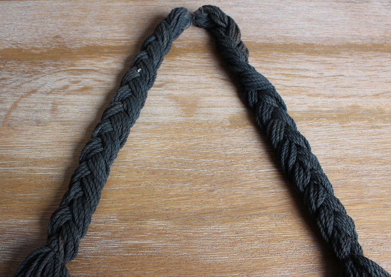 May include: A close-up of a dark green braided rope, with the ends of the rope forming a V-shape.