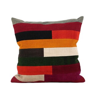 Könnte beinhalten: Drei dekorative Kissen mit einem geometrischen Muster aus bunten Streifen in den Farben Rot, Orange, Gelb, Grün, Blau und Weiß.