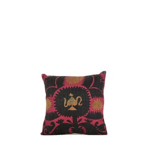 Pode incluir: Três almofadas decorativas com fundo rosa e bordado floral preto e branco. As almofadas apresentam um design verde e branco no centro.
