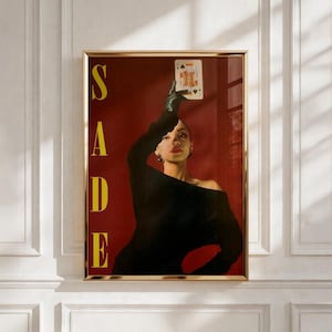 Op de afbeelding: Een verticale poster met een portret van een persoon in een zwart off-shoulder topje en een donkere handschoen, die een speelkaart boven het hoofd houdt. De achtergrond is dieprood, met het woord SADE in grote gele verticale letters.