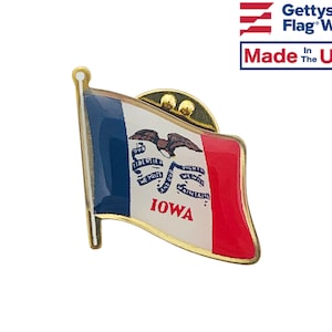 May include: Gold-colored pin featuring the Iowa state flag. The flag is blue, white, and red with a bald eagle and the words "Our Liberties We Prize And Our Rights We Will Maintain" in a scroll. The word "Iowa" is printed in gold at the bottom of the flag.