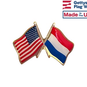 May include: A gold-colored pin with two crossed flags. The flag on the left is the American flag, and the flag on the right is the Dutch flag. The pin is made in the USA.