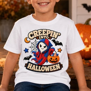 Puede incluir: Una camiseta blanca con el gráfico de un fantasma con capa roja y azul, sosteniendo un cubo de dulces de calabaza naranja. El diseño incluye una telaraña, murciélagos, estrellas y el texto CREEPIN' INTO HALLOWEEN en letras negritas.