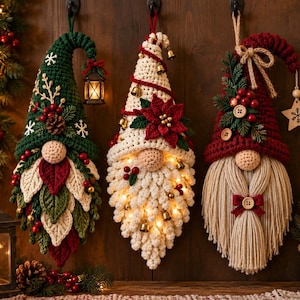 Könnte beinhalten: Drei hängende Wichtel-Ornamente in Häkeloptik. Der linke Wichtel ist grün mit einer Laterne, der mittlere ist cremefarben mit Lichtern und einem Weihnachtsstern, und der rechte ist rot mit einem Garnbart und Holzknöpfen.