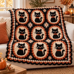 May include: A rectangular crochet blanket featuring a repeating pattern of nine black cats with orange bow ties, each centered within a cream-colored oval frame. The background is black with orange scalloped borders and small white star accents.