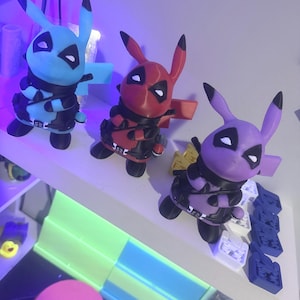 May include: Three figurines featuring a hybrid character design that combines the features of a yellow electric mouse creature with the mask and tactical gear of a red-suited mercenary. The figures are colored light blue, red, and purple.