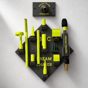 以下が含まれることがあります： ネオンイエローの歯科用ツールとアクセサリーのコレクションを展示する壁掛けボード。黒いボードには「DREAM CHASER」と「BRIGDREAMS」の文字があり、マイクのような装置を含む様々な器具がスロットに配置されています。