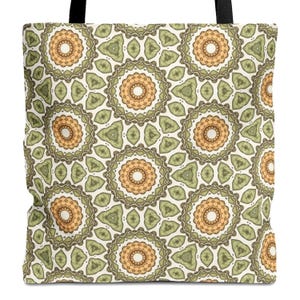 May include: A tote bag featuring a repeating geometric pattern of circular mandala-like shapes in shades of olive green and soft orange on a cream background. The design includes intricate scalloped edges and black fabric shoulder straps.