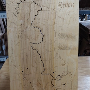 May include: A wooden map of the Toccoa River in Georgia. The map is laser-cut and shows the river's course through the mountains. The text on the map reads "The Toccoa River flows through some of the most spectacular mountain scenery in North Georgia for about 60 miles to where it crosses the state line into Tennessee.  Ellijay Ridge Lake is located approximately halfway between the Toccoa River's origin and its exit point from Georgia. The section of the river above Blue Ridge Lake is known as the upper Toccoa and the remaining portion in Georgia is called the lower Toccoa. When the river crosses the state line into Tennessee, it is known as the Ocoee River. The upper Toccoa is a popular location for canoeing, kayaking and tubing. The lower Toccoa is renowned for being the best tailwater trout fishery in Georgia."