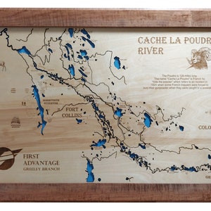 May include: A wooden map of the Cache La Poudre River in Colorado, with a blue water feature and a brown frame. The map includes the text "Cache La Poudre River", "Colorado", "First Advantage Greeley Branch", and "Horsetooth Reservoir".