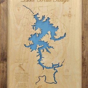 May include: A wooden map of Lake Blue Ridge in Georgia, with a blue outline of the lake and surrounding areas. The text "Lake Blue Ridge" is at the top of the map, and the text "Georgia" is at the bottom. The map also includes the text "The only lake south of the Great Lakes where Walleye are found." and information about the lake's depth, surface area, and shoreline.
