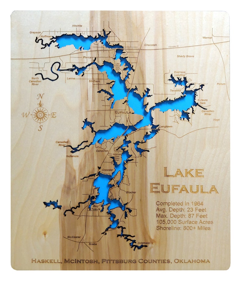 May include: A wooden map of Lake Eufaula in Oklahoma, with the lake's outline cut out and painted blue. The map shows the surrounding towns and rivers. The text "LAKE EUFAULA" is printed in large letters at the bottom of the map, along with information about the lake's size and depth. The text "HASKELL, MCINTOSH, PITTSBURG COUNTIES, OKLAHOMA" is printed at the bottom of the map.