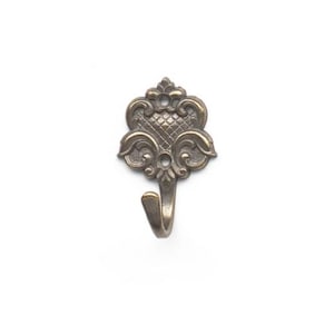 May include: A wall-mounted hook made of antique bronze-toned metal. The backplate features a symmetrical, ornate design with a central diamond-patterned texture, curved scrollwork, and two circular screw holes for mounting purposes.