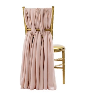 May include: A gold metal chair with a blush pink fabric sash tied around the back.