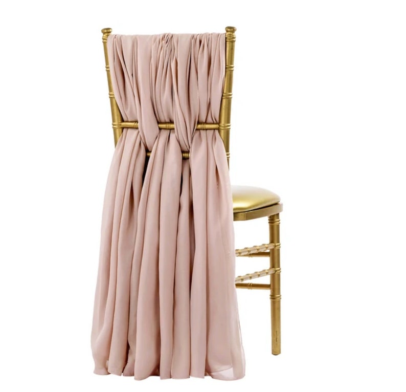 May include: A gold metal chair with a blush pink fabric sash tied around the back.