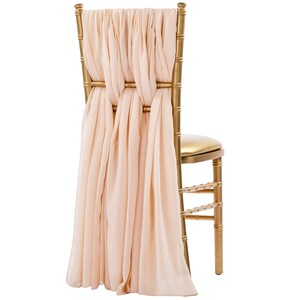 May include: A gold chiavari chair with a blush pink satin sash tied in a bow at the back of the chair.