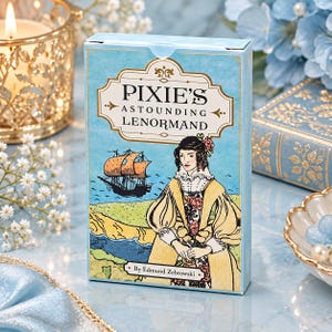 May include: A rectangular deck of cards titled Pixie's Astounding Lenormand by Edmund Zebrowski. The box features a light blue background with a gold-bordered label, a black sailing ship on the water, and an illustration of a person in a yellow coat.