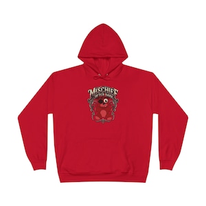 May include: A bright red hooded sweatshirt featuring a central graphic of a dark red teddy bear with one eye patch and one large eye. The text "MISCHIEF AFTER DARK" is printed in a stylised font above the bear, all enclosed within an ornate frame.