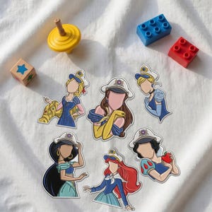 May include: A collection of six die-cut stickers featuring faceless female characters wearing white sailor-style hats. The characters have distinct hair colors and outfits, including blue dresses, yellow gloves, and a red apple, arranged on a white fabric surface.