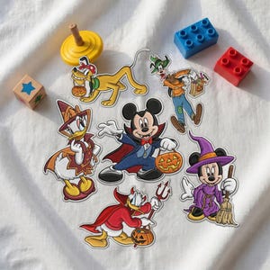 May include: A collection of embroidered patches featuring Disney characters in Halloween costumes, including Mickey Mouse as a vampire, Minnie Mouse as a witch, Donald Duck as a devil, Daisy Duck as a witch, Goofy as a scarecrow, and Pluto.