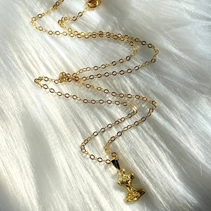 May include: A gold chain necklace with a small gold pendant shaped like a hammer.